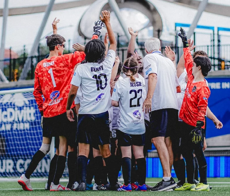 United Genuine FC players and coaches in a team huddle